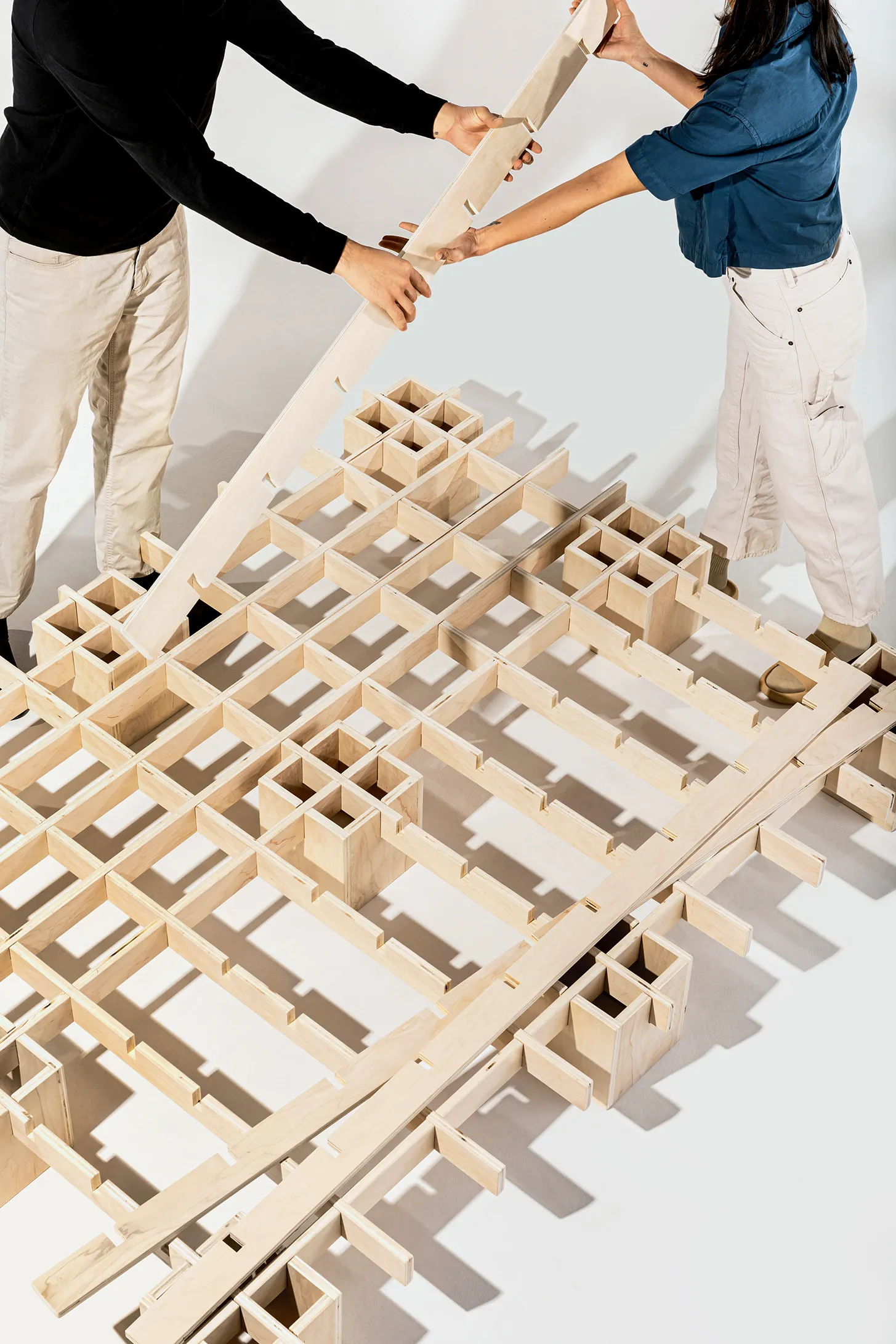 Two people building the Tic Tac Toe bed by Quagga Designs.
